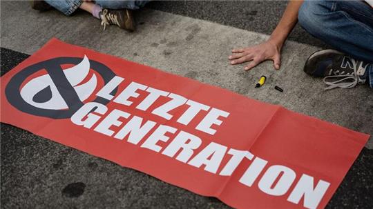 Ein Aktivist der Gruppe „Letzte Generation“ blockiert eine Kreuzung.