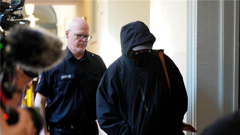 Promi-Prozess um Entführung der Block-Kinder Ein Angeklagter wird von einem Polizisten zum Gerichtssaal begleitet.
