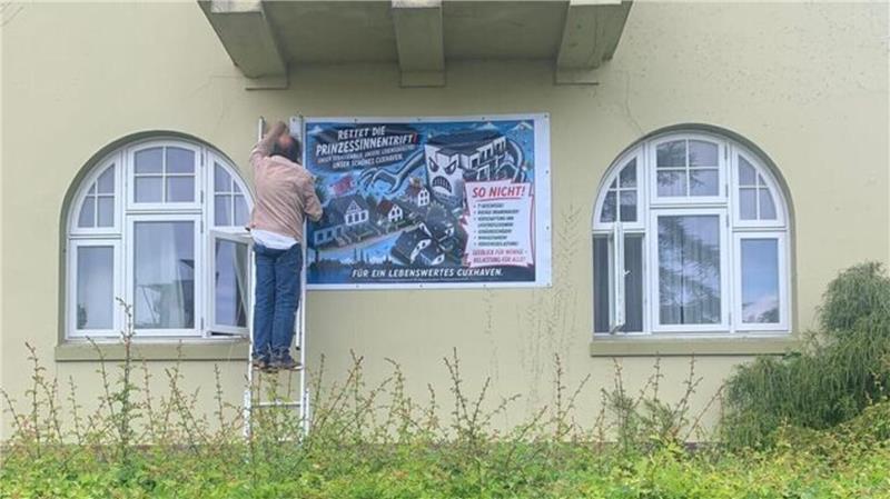 Neue Ferienwohnungen – Nordsee-Anwohner schalten Anwalt ein Ein Anwohner befestigt ein Protestplakat gegen das umstrittene Bauprojekt in der Prinzessinnentrift - Symbol für den Widerstand der Nachbarschaft.