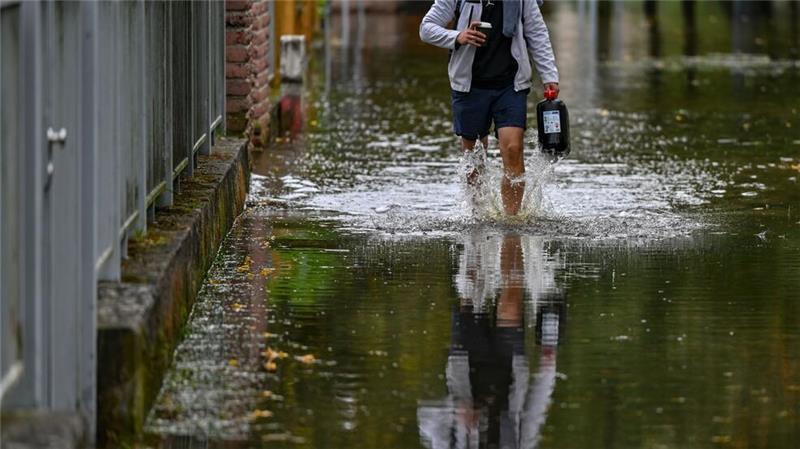 Ein Anwohner einer überfluteten Straße in Frankfurt Oder watet durch das Wasser.