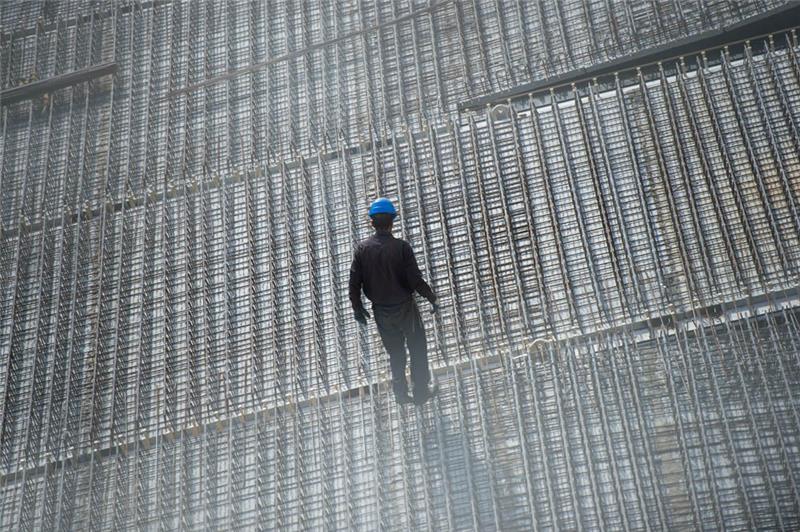 Ein Arbeiter steht auf einer Baustelle. Foto: Arne Immanuel Bänsch/dpa