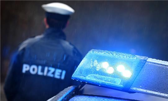 Ein Polizist steht neben einem Streifenwagen.