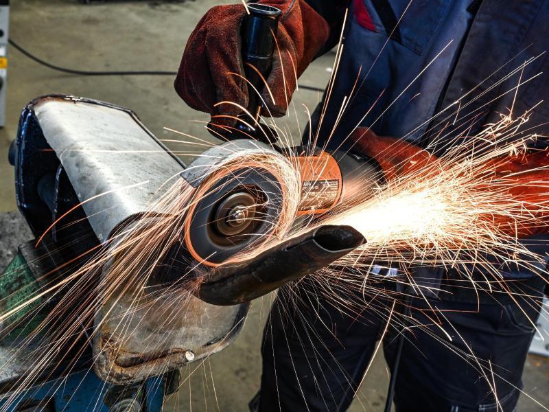 Ein Auszubildender im KFZ-Handwerk schneidet in einem Ausbildungszentrum mit einer Flex einen alten Auspuff auf. Foto: Felix Kästle/dpa/Symbolbild
