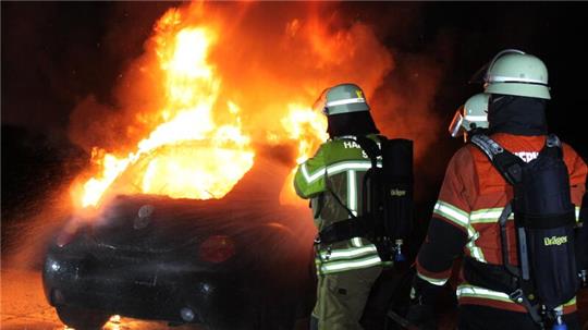 Ein Auto brennt - die Feuerwehr kommt und löscht. Die Chefs der Truppe erhalten mehr Geld.