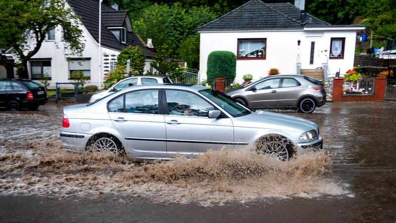 Ein Auto fährt im Stadtteil Hamburg-Lohbrügge durch eine überschwemmte Straße.