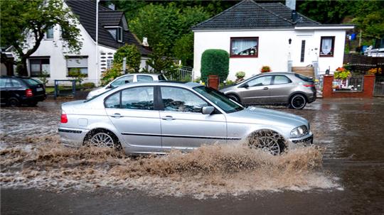 Ein Auto fährt im Stadtteil Hamburg-Lohbrügge durch eine überschwemmte Straße.