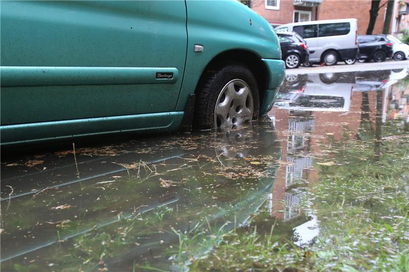 Ein Auto steht in einer großen Pfützen mit aufgestautem Regenwasser. Eine Gewitterfront ist am Samstagnachmittag über Hamburg und Schleswig-Holstein gezogen. Foto: Bodo Marks/dpa