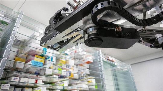 Ein Automat sucht in einer Apotheke ein Medikament für einen Kunden aus dem Warenlager heraus.