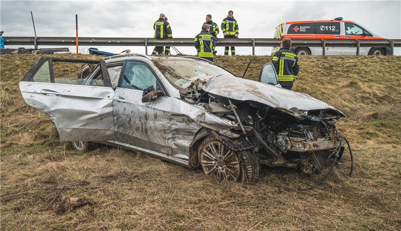 Ein Autowrack steht nach einem Reifenplatzer und anschließendem Kontrollverlust auf der Böschung neben der Fahrbahn.