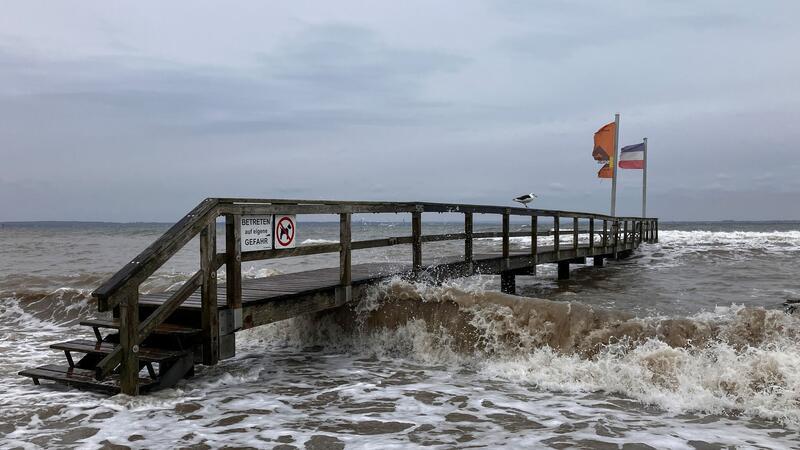 Ein Badesteg in Niendorf wird von Wellen umspült. Die Menschen an der schleswig-holsteinischen Ostseeküste müssen sich auf eine schwere Sturmflut einstellen.