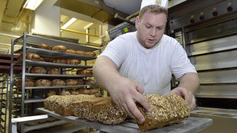 Ein Bäcker begutachtet sein Brot in der Backstube.