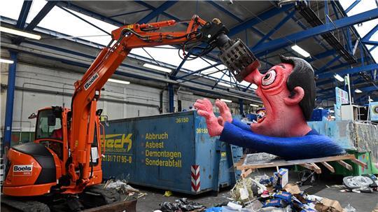 Ein Bagger hebt in Düsseldorf eine Pappfigur eines Rosenmontagszugs in den Müll. Nachdem die Motive zahlreiche Zuschauer begeisterten, werden sie abgerissen.