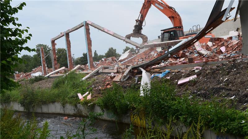 Ein Bagger reißt eine Wand des früheren Lidl-Marktes in Altkloster ab. Bei den Abrissarbeiten fallen einzelne Steine in den Wasserlauf der Fischtreppe.