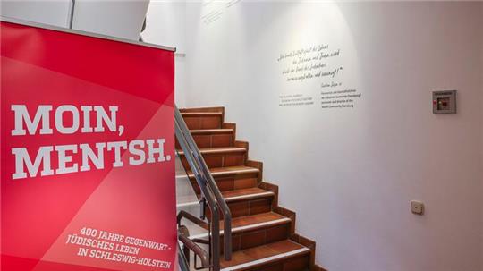 Ein Banner mit der Aufschrift „Moin Mentsh“ steht neben einer Treppe im Jüdischen Museum.