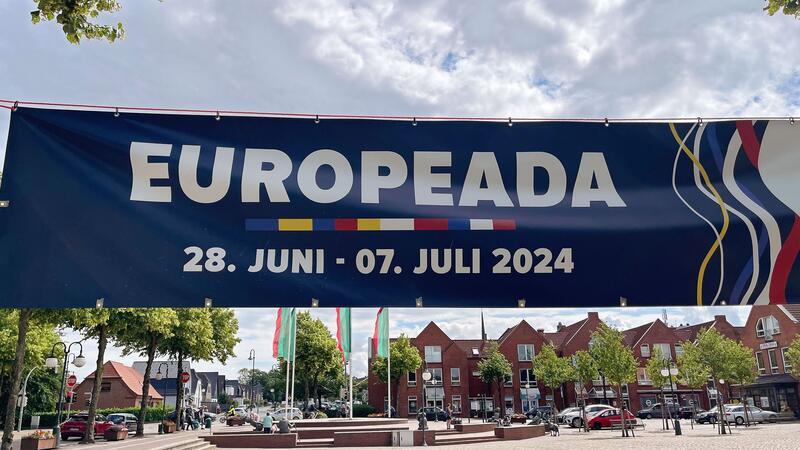 Die andere EM: Nationale Minderheiten spielen im Norden Ein Banner weist am Marktplatz auf die Fußball-EM der autochthonen nationalen Minderheiten Europeada hin.