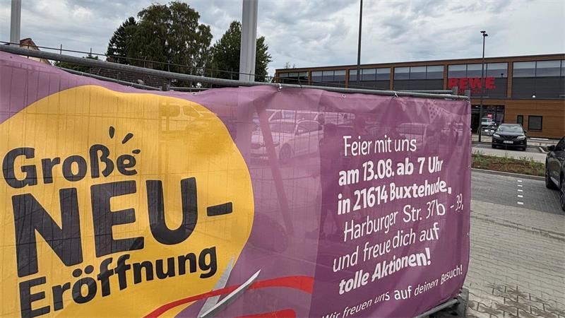 Ein Banner weist auf die Neueröffnung des Rewe-Markts an der Harburger Straße hin.