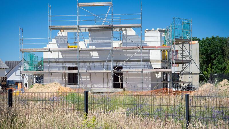 Ein Baugerüst steht an der Fassade eines sich im Bau befindlichen Einfamilienhauses.