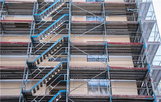 Ein Baugerüst steht an einem Haus-Neubau mit Wohnungen. Foto: Daniel Bockwoldt/dpa