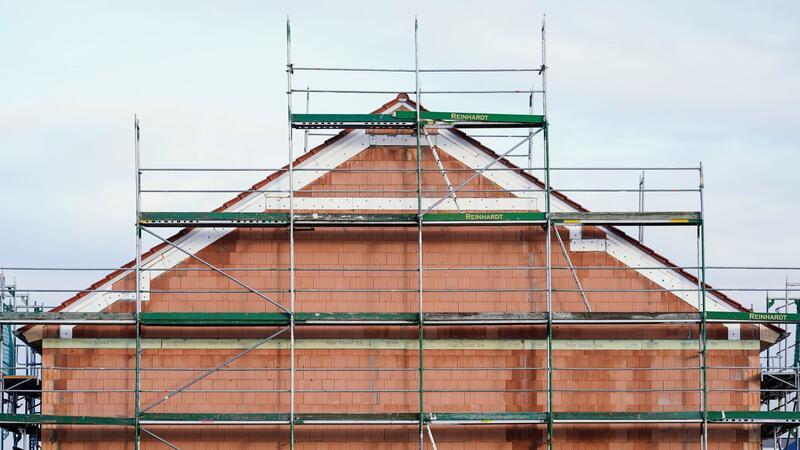 Bauspar-Boom hält an - Entwicklung verliert aber an Tempo Ein Baugerüst steht in einem Neubaugebiet an einem Rohbau.