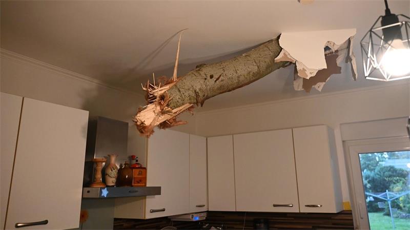 Ein Baumstamm ragt nach einem Unwetter in Fürstenwalde-Süd aus der Decke in der Küche eines Wohnhauses.