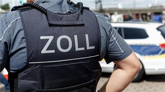 Ein Beamter trägt während seines Dienstes eine Schutzweste mit der Rückenaufschrift „Zoll“.