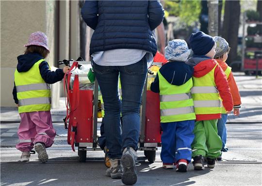 Ein Betreuerin läuft mit mehreren Kleinkindern durch die Stadt. Symbolbild