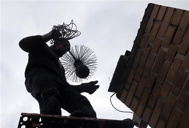 Ein Bezirksschornsteinfeger reinigt den Schornstein eines Wohnhauses. Foto: Wolfgang Kumm/dpa