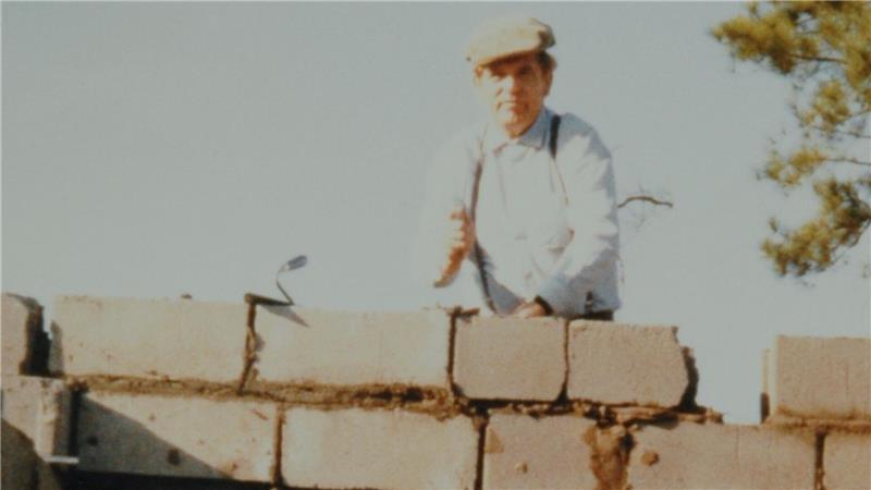 Ein Bild aus den 80er Jahren: In der oberen Hälfte des Fotos mauert Gustav Viebrock in Afrika an einem Gebäude.