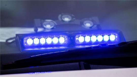 Ein Blaulicht leuchtet unter der Frontscheibe eines Einsatzfahrzeugs der Polizei.