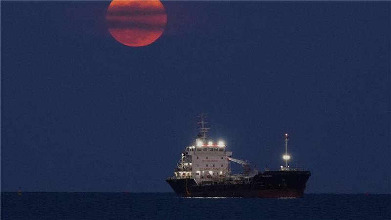 Ein Blutmond geht über dem Mittelmeer bei Limassol auf, wo ein Schiff vor Anker liegt.