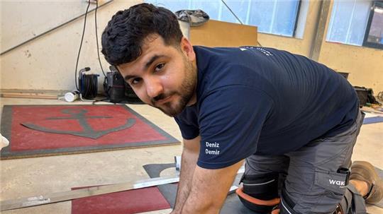 Ein Bodenverleger verbringt viel Zeit auf den Knien: Deniz Demir beim Fertigen der PVC-Platte.