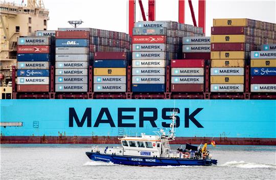 Ein Boot der niedersächsischen Wasserschutzpolizei fährt vor dem Containerschiff „Morten Maersk“ der dänischen Reederei Maersk Line entlang, das an einer Kaimauer am Containerterminal JadeWeserPort liegt. Foto: Hauke-Christian Dittrich/dpa