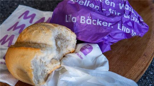 Ein Brötchen aus einer „Lila Bäcker“-Filiale liegt auf einem Frühstücksbrett.