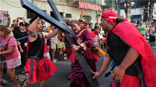 Ein Büßer mit einem Holzkreuz während eines Passionsspiels in Mandaluyong, das die Leiden Jesu Christi nachstellt. Die Szene spielt am Gründonnerstag im Rahmen der Karwochen-Feierlichkeiten.