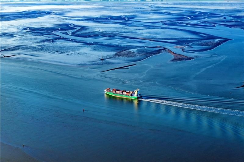 Martin Elsens neue "Luftnummern": Was der Stader Fotograf 2023 plant Ein Containerschiff passiert die Außenweser im Wattenmeer an der Wurster Küste.
