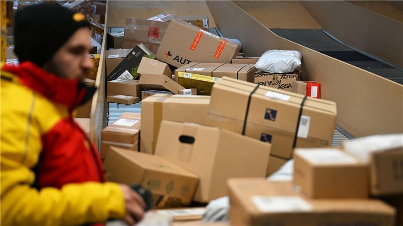 Ein DHL-Paketbote ist in einer Zustellbasis mit einer Vielzahl an Paketen beschäftigt. Der Logistikkonzern hat Jahreszahlen für 2025 vorgelegt, er hat profitablere Geschäfte gemacht als zuvor.