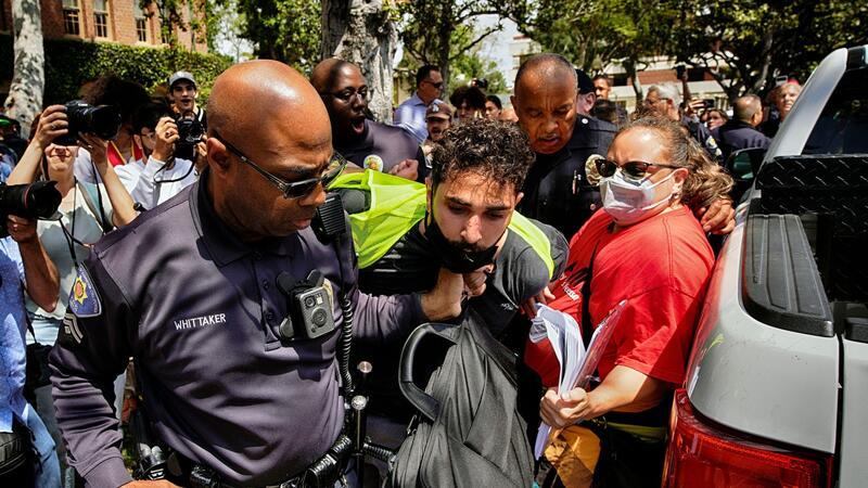 Ein Demonstrant der University of Southern California wird während einer pro-palästinensischen Besetzung des Alumni-Parks in Los Angeles von Beamten des USC Department of Public Safety festgehalten.