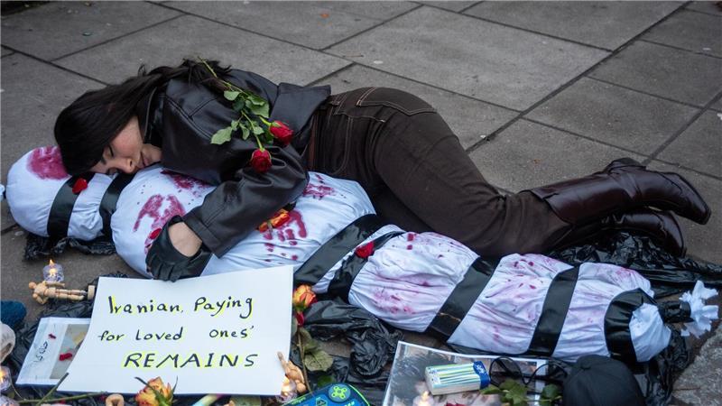 Ein Demonstrant liegt mit einem menschlichen Leichnam, der ein Opfer symbolisiert, auf dem Boden.