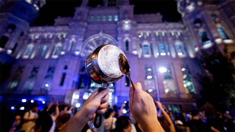 Ein Demonstrant schlägt während eines Protests für das Recht auf Wohnen vor dem Madrider Rathaus mit einem Löffel auf einen Topf.