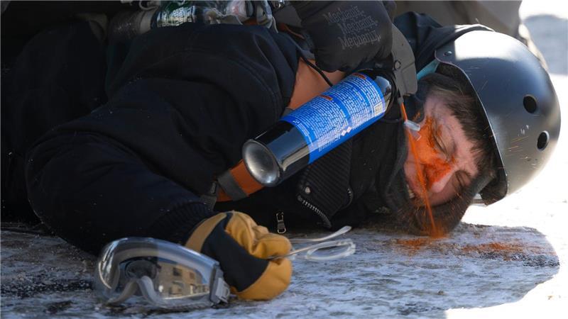 Ein Demonstrant wird aus nächster Nähe mit Pfefferspray besprüht.