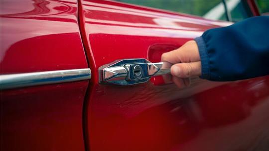 Eine Hand an einem Griff einer Autotür.