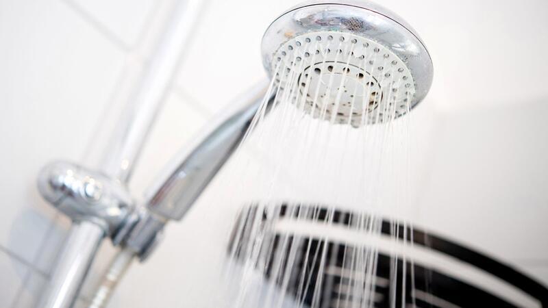 Ein Duschkopf hängt in einer Dusche in einem Badezimmer.