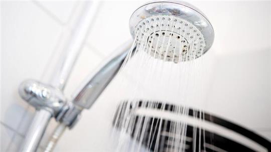 Ein Duschkopf hängt in einer Dusche in einem Badezimmer.