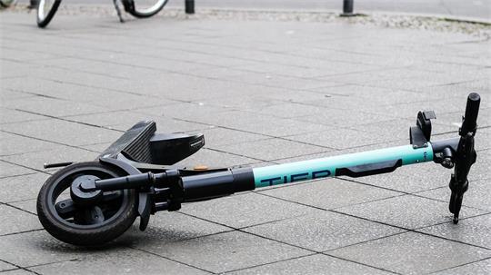 Ein E-Scooter liegt umgekippt mitten auf einem Gehweg (Symbolbild)