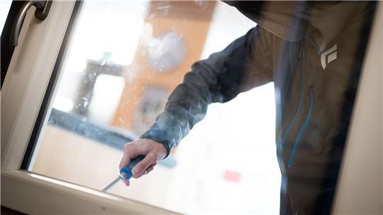 Ein Einbrecher versucht, mit einem Schraubenzieher ein Fenster aufzuhebeln (Symbolbild).