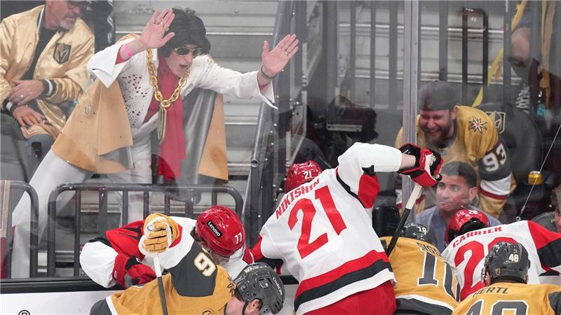 Ein Elvis-Imitator schlägt auf die Scheibe, während die Spieler um den Puck kämpfen.