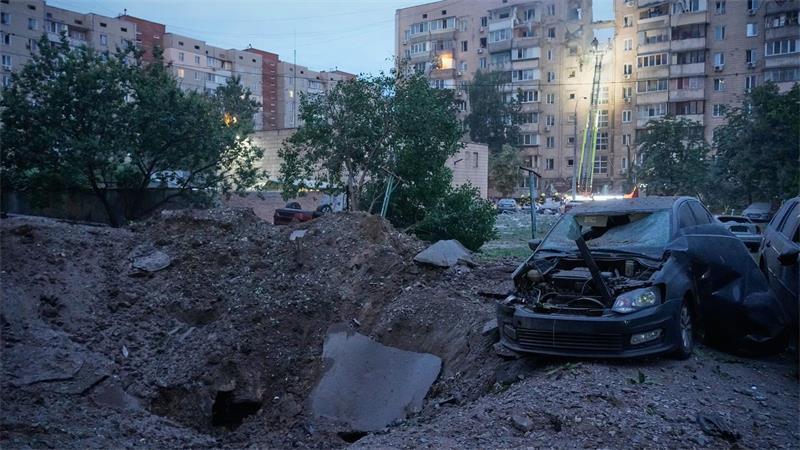Ein Explosionskrater und beschädigte Autos sind neben einem Wohnhaus zu sehen.