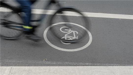 Ein Fahrradfahrer fährt auf dem Radfahrstreifen einer Fahrbahn. 
