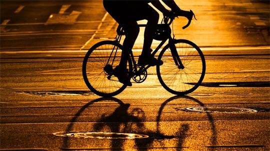 Ein Fahrradfahrer fährt auf einer Straße, auf der sich Regenwasser gestaut hat. (zu dpa: «Stürmische Böen und Schauer: Wetter bleibt wechselhaft»)