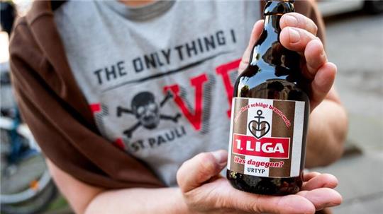 Ein Fan hält eine Bierflasche mit der Aufschrift „1.Liga“.